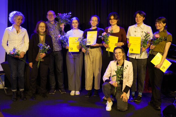 Acht Frauen und ein Mann stehen auf einer Bühne. Sie halten Urkunden und Blumen in den Händen.