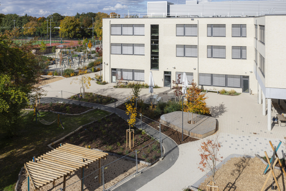 Bild © Giulia Iannicelli Schulhof des Schulcampus Werderau in der Maiacher Straße im Oktober 2025 mit Spielelementen im Vordergrund und Sportplatz im Hintergrund., Bild © Giulia Iannicelli