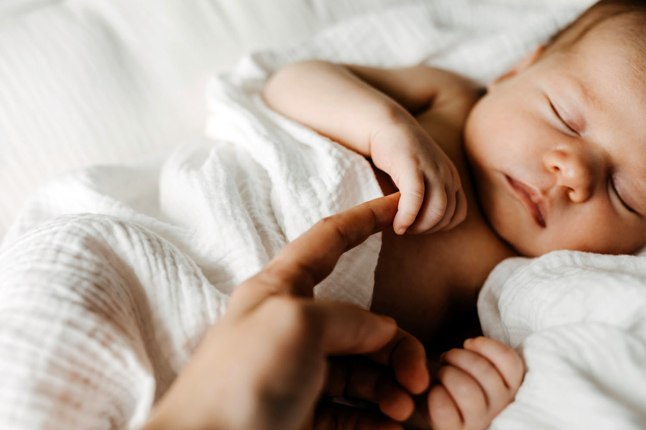 Bild © Natalia Bostan / Adobestock Schlafendes Baby, eine Frauenhand hält eines der Händchen., Bild © Natalia Bostan / Adobestock