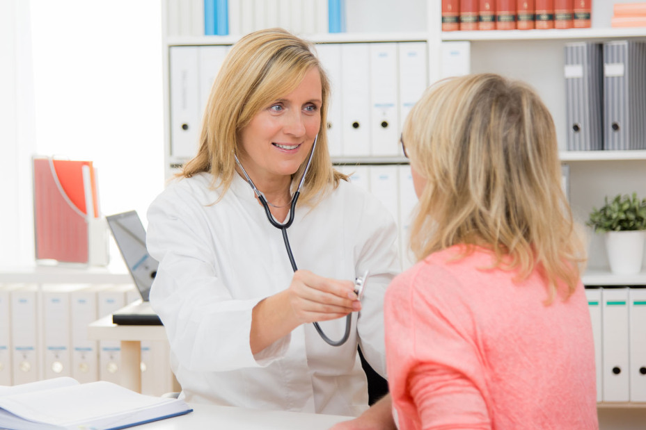 Eine Hausärztin hört eine Patientin mit einem Stethoskop ab.