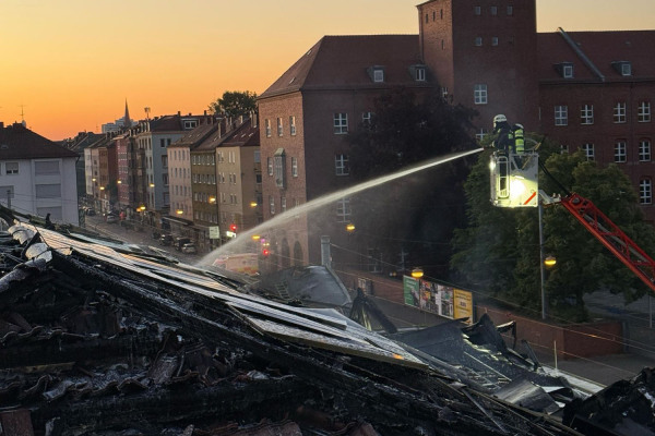 Ein Feuerwehrmann auf einer Leiter löscht den Brand im Dach der Turnhalle der Wiesenschule.