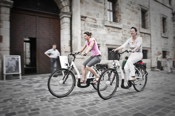 Zwei Frauen, die auf E-Bikes unterwegs durch die Stadt sind.