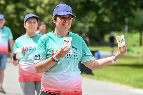 Eine freiwillige Helfende händigt Getränke beim Metropolmarathon aus.
