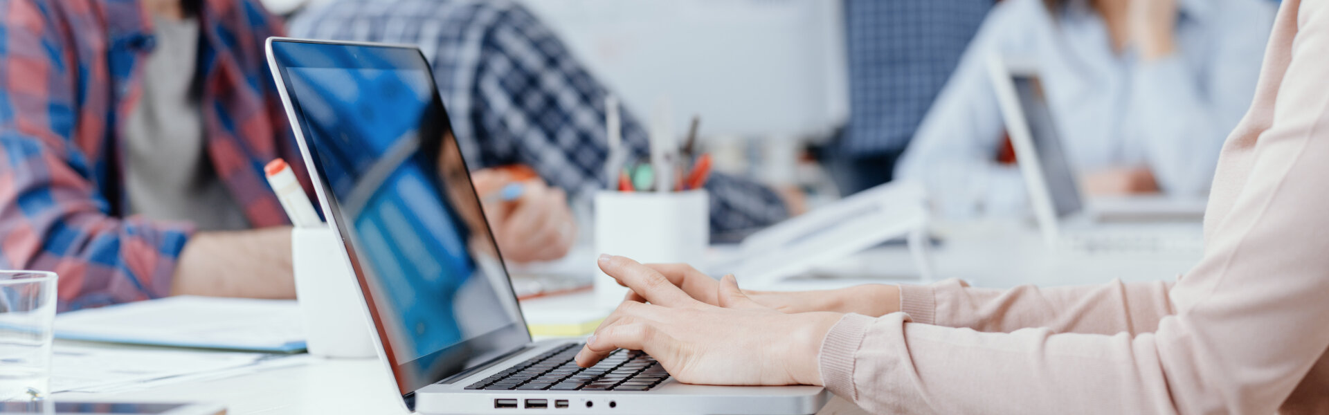Young business team meeting in the office and working, a woman is using a laptop on the foreground: start up and innovation concept