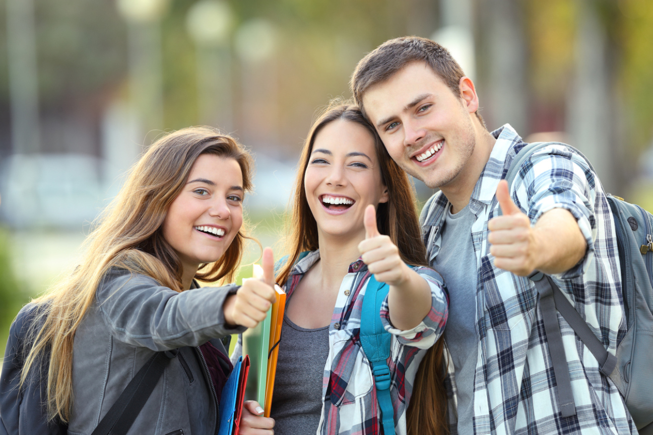 Three happy students looking at you with thumbs up in an university campus, Bild © AntonioGuillem