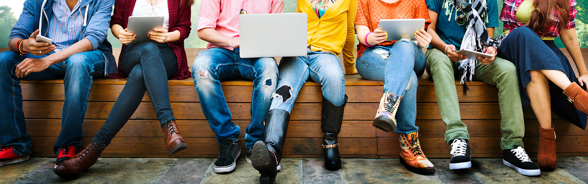 Schüler sitzen im Pausenhof, man sieht nur die Beine