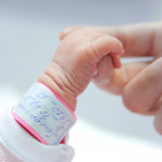 Hand eines Neugeborenen wird gehalten
