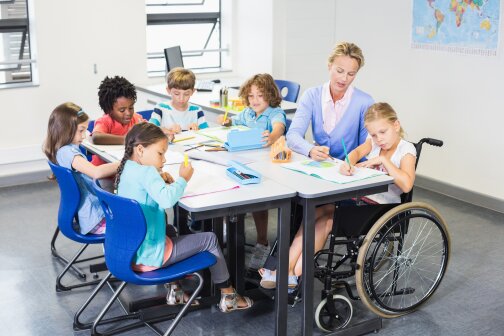 Teacher helping kids with their homework in classroom