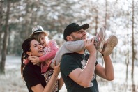 Mutter und Vater tragen ihre Tochter auf Händen.