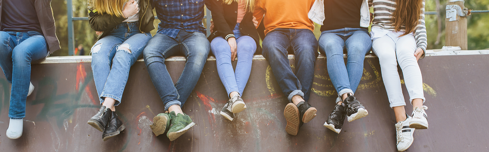 Jugendliche sitzen auf einer Mauer, man sieht nur die Beine und die Füße.
