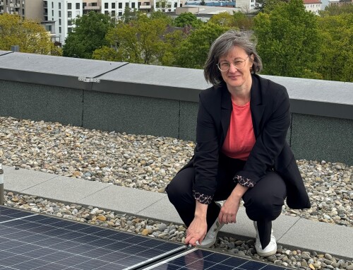 Frau Walthelm hockt vor einer PV-Anlage