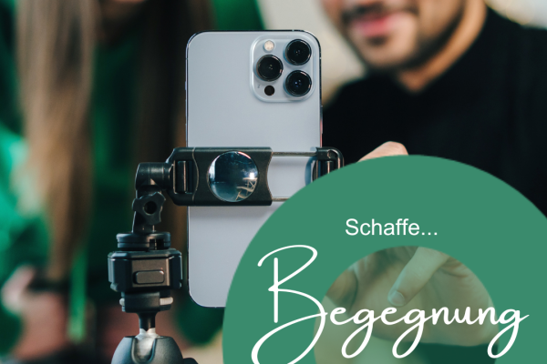 Ein junger Mann tippt auf ein Smartphone, das auf einem Ständer fixiert ist. Eine junge Frau sieht ihm dabei zu,