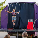 Eine Zirkusartistin steht auf einer LKW-Bühne