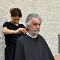 Eine Friseurin schneidet einem Mann Haare