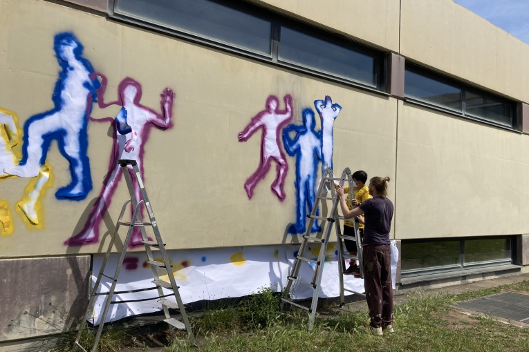 Mit Leitern werden Schablonen an die Hauswand geklept und die Ko