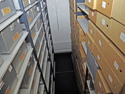 Das Bild zeigt einen Raum im Stadtarchiv Nürnberg. In dem Raum stehen hohe Regale. In den Regalen stehen Kisten und Kartons.