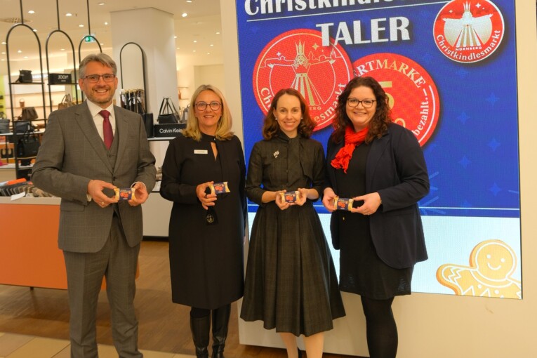 Der Leiter der Nürnberger Märkte Marco von Dobschütz-Dietl, Geschäftsleiterin Wöhrl Ludwigsplatz Carola Möller, Wirtschafts- und Wissenschaftsreferentin Dr. Andrea Heilmaier und für den Christkindlesmarkt zuständige Mitarbeiterin bei den Nürnberger Märkten Verena Beck präsentieren den neuen Christkindlesmarkt-Taler (v.l.n.r.).