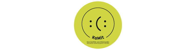 Grüner Kreis, auf dem ein liegender Smiley abgebildet ist, der von links betrachtet fröhlich und von rechts betrachtet traurig aussieht; darunter der Name KoMit und dessen Beschreibung