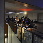 Im Innenraum des Neuen Museums stehen mehrere Instrumente auf dem Boden und im Hintergrund unterhalten sich mehrere Personen miteinander.