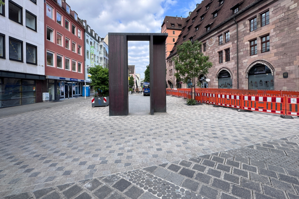 Die Neugestaltung der nördlichen Platzhälfte soll den Hallplatz mit neuem Granitbelag und zusätzlichen Aufenthaltsflächen weiter aufwerten. Aufgrund eines Lieferengpasses beim benötigten Granitpflaster müssen die Arbeiten auf der Baustelle vorübergehend pausieren. Alle Geschäfte können über sogenannte Grabrücken oder asphaltierte Flächen erreicht werden.