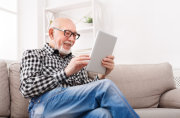 Älterer Herr liest Neuigkeiten auf dem Tablet