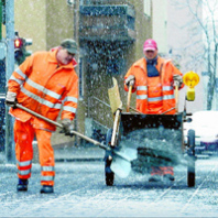 Zwei SÖR-Mitarbeitern streuen Splitt und sichern so den Gehweg