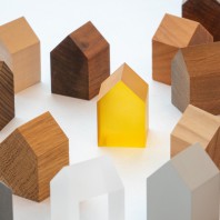 Mehrere Miniaturhäuschen aus Holz  mit einem kleinen leuchtenden Holzhäuschen in der Mitte