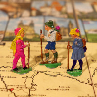 Historisches Brettspiel aus der Sammlung Mensekamp. Das Spielbrett zeigt eine Karte Frankens mit Wanderwegen. Auf dem Brett befinden sich drei bunt bemalte Figuren. Es sind Kinder in Wanderkleidung.