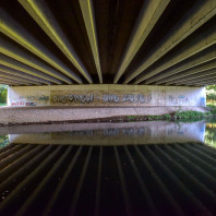 Im Dunkel einer breiten Autobahnbrücke der A 3 erreicht die Pegnitz rund 95 Kilometer nach ihrer Quelle städtisches Gebiet.