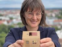 Britta Walthelm hält Haus Modell mit PV Anlage auf dem Dach