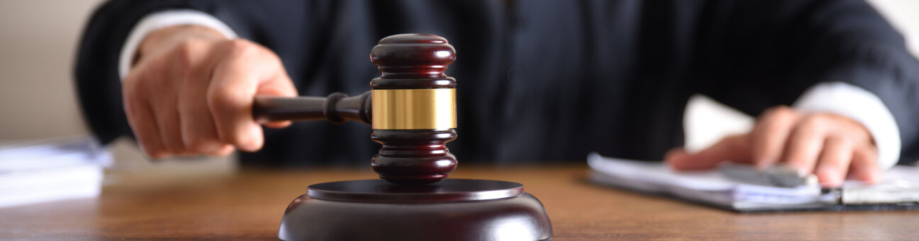 Detail of a judge passing sentence by hitting with the gavel on a wooden table closeup. Front view © David Izquierdo / Adobe Stock