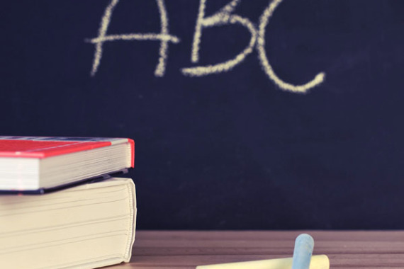 Kreiden und Bücherstapel auf einem Pult, im Hintergrund eine Ta