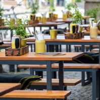 Holzbänke und Tische vor einem Restaurant in der Innenstadt.