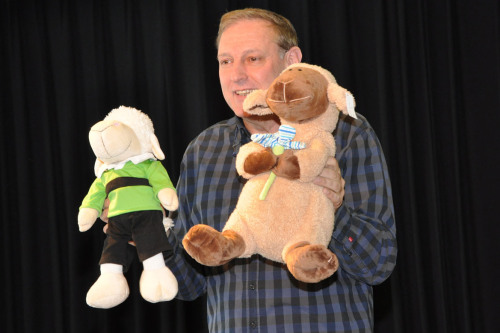 Ein Mann auf einer Bühne hält zwei Kuscheltiere in die Höhe.