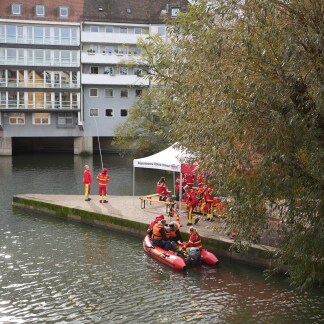 ( Bild: Hanna Quitterer ) Infostand der Deutschen Lebens-Rettungs-Gesellschaft (DLRG) auf der Liebesinsel mit Rettungsboot an der Anlegestelle.