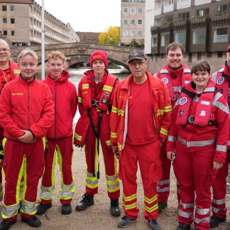 ( Bild: Hanna Quitterer ) Gruppenfoto mit acht Mitgliedern der DLRG in roter Kleidung auf der Liebesinsel.