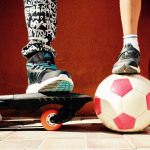 Zwei Kinder mit einem Skateboard und einem Fußball.