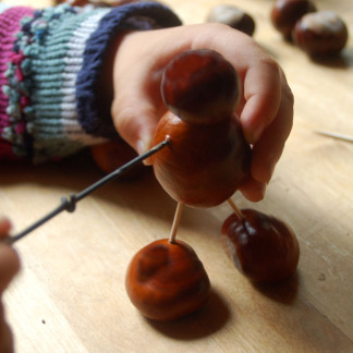 ( Bild: thingamajiggs - stock.adobe.com ) Kind bastelt Kastanienmännchen