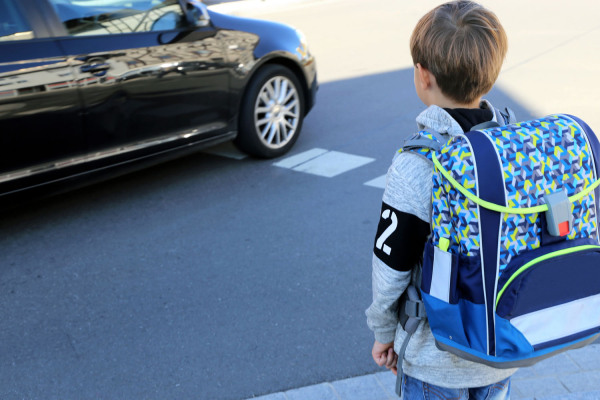 Ein Schulkind überquert auf seinem Schulweg eine Straße.