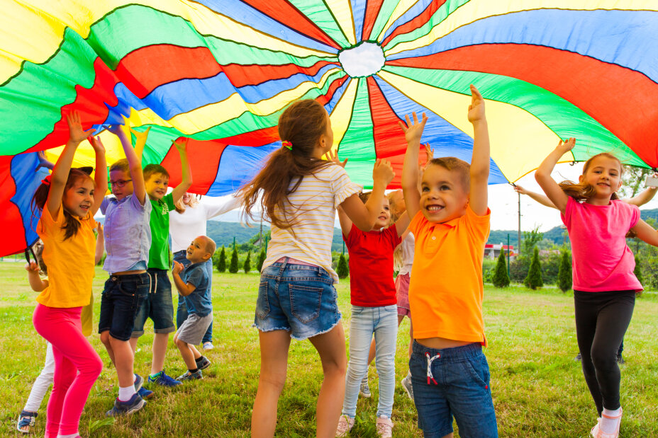 Bild © AdobeStock Happy laughing boy standing hands-up under colorful cloth. Children having fun on the birthday party, Bild © AdobeStock