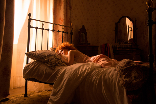 Filmstill aus "Das Glück der Welt": Eine Frau liegt auf einem Bett und schläft.