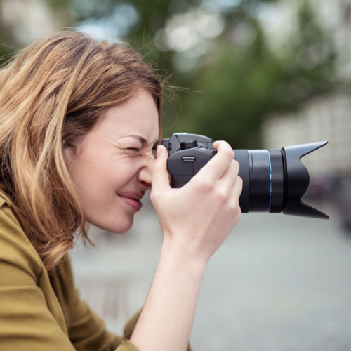 Eine Frau fotografiert in der Stadt mit einer Digitalkamera. © contrastwerkstatt - stock.adobe.com