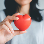 Frau hält ein rotes Herz in der Hand.