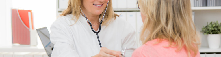 Eine Hausärztin hört eine Patientin mit einem Stethoskop ab.