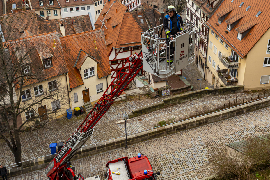 Bild © Daniel Mildner / Feuerwehr Nürnberg An der Außenfassade der Burg hebt eine Drehleiter einen Mitarbeiter in die Höhe., Bild © Daniel Mildner / Feuerwehr Nürnberg