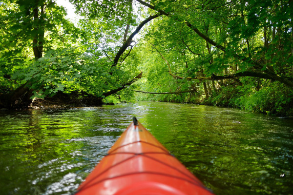 Ein Mensch paddelt mit einem Kajak auf einem Fluss.