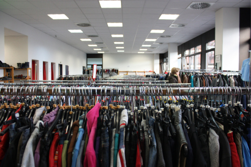 Blick in den großen Kleiderladen der BRK Nürnberg. Gebrauchte Kleidung wird auf unzähligen Kleiderstangen zum Verkauf angeboten.