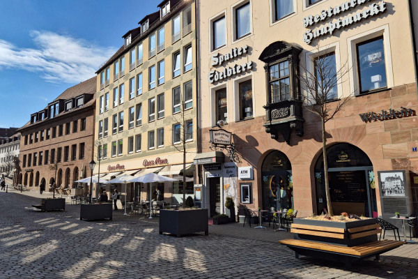 Mobile Bäume, zum Teil mit Bänken, stehen seit März 2026 an der Westseite des Hauptmarkts.