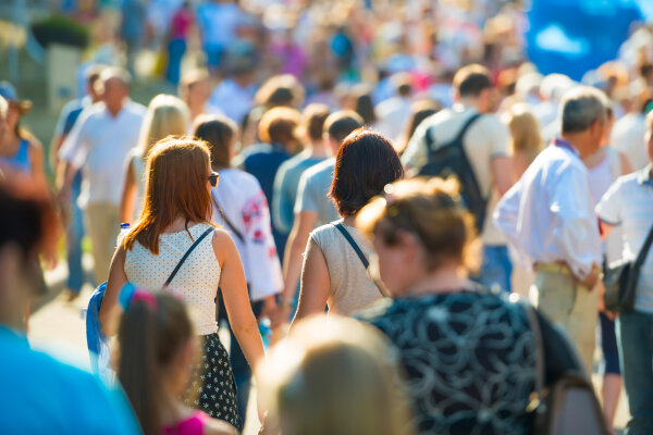 Crowd of people walking on the sunny and busy city street. Soft focus