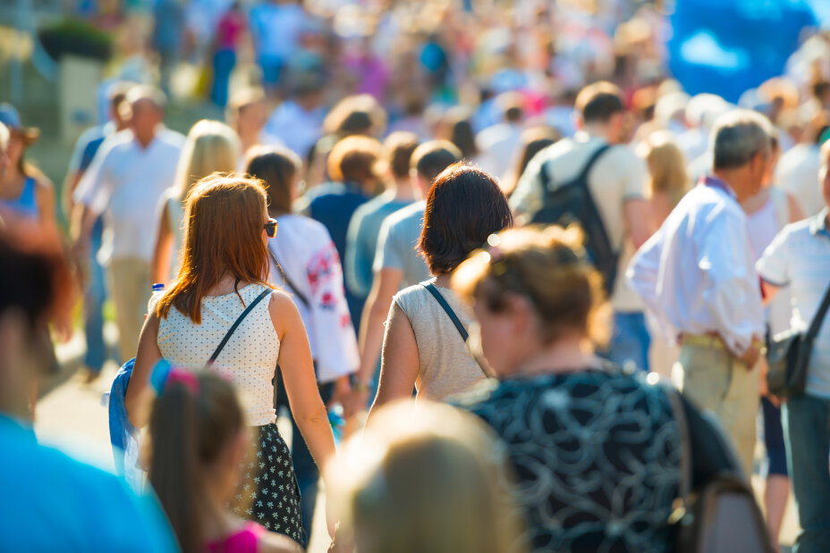 Crowd of people walking on the sunny and busy city street. Soft focus